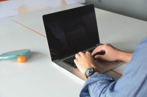 A man with his laptop on ping pong table
